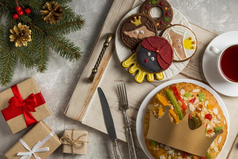 cartoon face designed cookies on a plate with a fruit cake and a tea beside with little gifts and christmas decorations