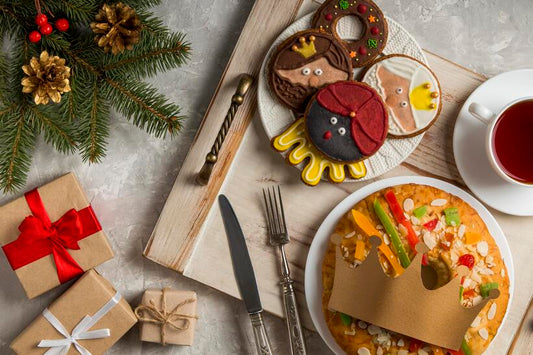 cartoon face designed cookies on a plate with a fruit cake and a tea beside with little gifts and christmas decorations