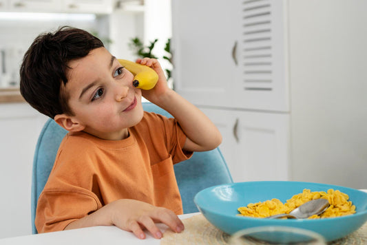 toddler eating lunch holding a banana